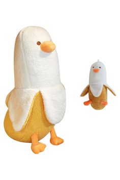 two stuffed animals that are standing next to each other on a white surface with one penguin in the foreground