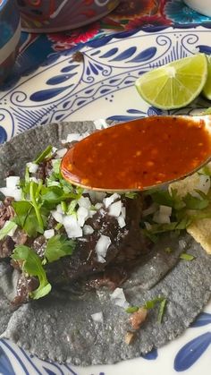 a tortilla topped with meat, lettuce and sauce on a plate