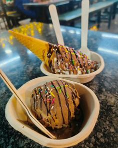 two bowls filled with ice cream and topped with sprinkles on a table