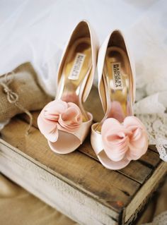 two pairs of shoes with pink bows on them sitting on top of a wooden box