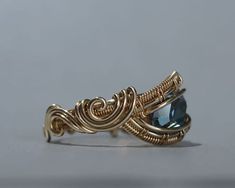 a gold ring with a blue topazte stone in it's center on a gray background