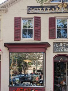 a store front with red shutters and flowers in the window