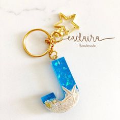 the letter j is made out of glass and has a starfish charm on it