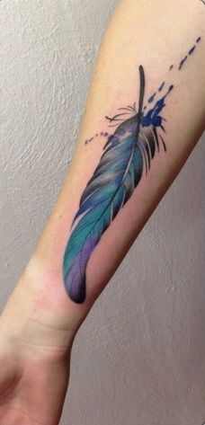 a person with a tattoo on their arm that has a blue and green feather on it