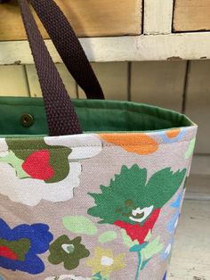 This small tote is made out of gorgeous floral cotton canvas 🍃 (beautiful colours) with green 🦆 drill cotton lining 🍁  Features handles made out of brown canvas webbing. brass magnetic 🧲 snap closure.  A cute tote to take out to a cafe or use it as a craft project bag 🧶  🧵 Dimensions- 36cm w (at top) x 24cm h x 10cm 🧵 Green Canvas Bag For Spring, Green Canvas Bag For Spring Shopping, Spring Green Canvas Bag For Shopping, Green Canvas Tote Bag With Canvas Lining, Green Cotton Canvas Tote Bag, Green Cotton Bag With Leather Handles, Vintage Green Cotton Bag, Rectangular Cotton Canvas Bag With Rolled Handles, Green Cotton Bags For Spring