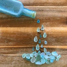 some blue glass pieces and a bottle on a wooden surface with water drops coming from them