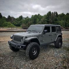 a gray jeep parked on top of a gravel field