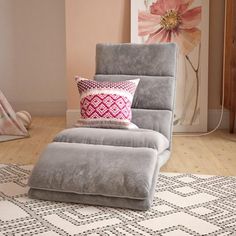 a pink recliner chair sitting on top of a wooden floor next to a white rug