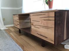 a wooden sideboard sitting on top of a hard wood floor next to a window