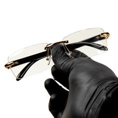 a pair of glasses being held up to the side by someone's gloved hand