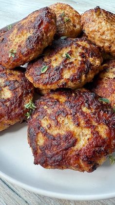 some meat patties on a white plate with parsley sprinkled on top