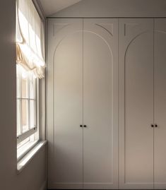 an empty room with white cupboards next to a window and carpeted flooring