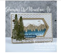 a card with mountains and trees in the background, on top of a white table