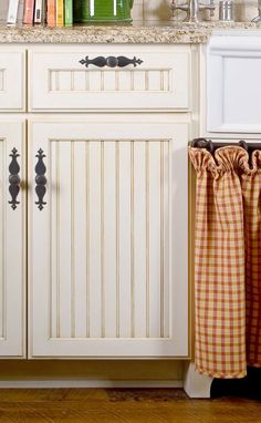 a kitchen with white cabinets and brown checkered curtains on the window sill next to an oven