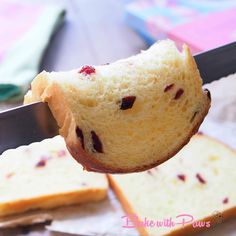 someone is holding a piece of bread with cranberry toppings on it while cutting into slices