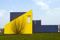 a yellow and blue house sitting on top of a lush green field