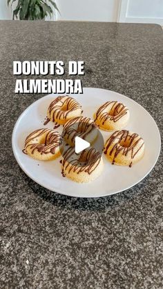 donuts with chocolate drizzled on them sitting on a white plate that says donuts de almendraa