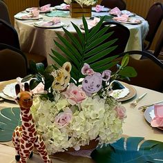 a giraffe figurine sitting on top of a table next to a vase filled with flowers