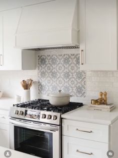 a stove top oven sitting inside of a kitchen next to white cabinets and counter tops