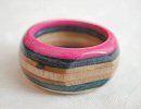 a close up of a wooden ring on a white surface with pink and blue stripes