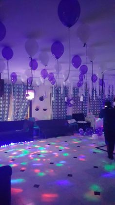 a party room with balloons and streamers on the ceiling, lights in the background