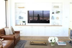 a living room filled with furniture and a flat screen tv mounted on a wall above a fireplace