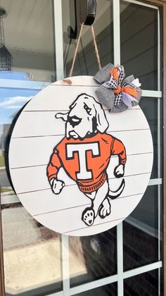 a sign hanging from the side of a building with a dog wearing an orange shirt