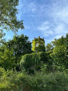 a tall green building surrounded by trees and bushes