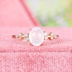 a white pearl and diamond ring sitting on top of a pink blanket