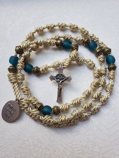 STELLA MARIS is made with light gold nylon twine, antique bronze spacers, and teal Ghana African recycled sea glass beads. It includes a silver-toned Miraculous Medal Crucifix with blue enamel detail and Stella Maris medal. Both pendants are attached to stainlss steel double loop jump rings for strength. Knotted rosaries are the kind of rosaries you can do life with. They can be stuffed in a pocket or purse and hold up beautifully to daily use. Do you like to handle or turn the knots or beads while praying? These rosaries won't break. The addition of Our Father beads, a miraculous medal and a real crucifix help encourage prayer.