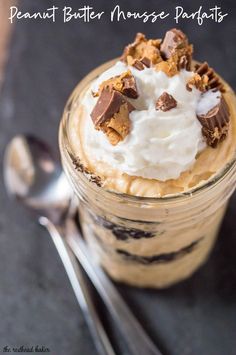 a dessert in a glass with whipped cream and chocolate chips on top, next to a spoon