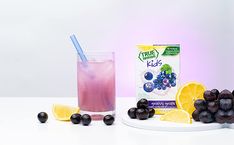 blueberries and lemons are next to a carton of juice on a plate