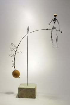 an artistic sculpture is displayed on a white surface with a wooden block and metal wire