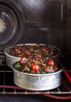 two metal pans filled with food cooking in an oven