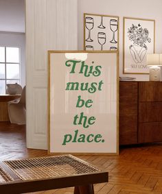 this must be the place sign in front of a table with chairs and pictures on it