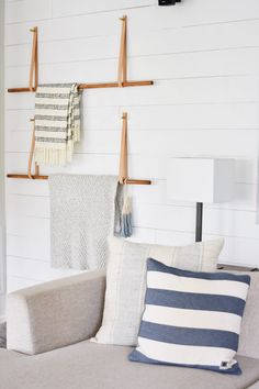 a couch with pillows and blankets hanging on the wall next to two wooden pegs