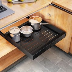 pots and pans are sitting on an open drawer in the middle of a kitchen