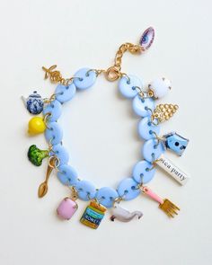 a blue bracelet with various items on it and a gold plated charm around the clasp