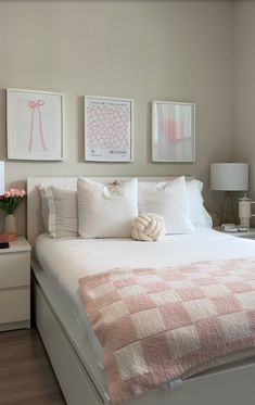 a white bed topped with pillows and blankets next to two nightstands filled with flowers