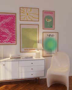 a white chair sitting in front of a wall filled with pictures and art on it