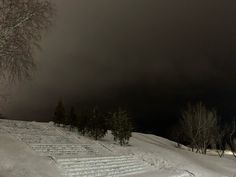 a snow covered hill with steps leading up to the top and trees in the background