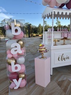 a pink and gold baby shower is set up on the floor next to an ice cream stand