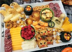 an assortment of food on a platter with cheeses, crackers and fruit