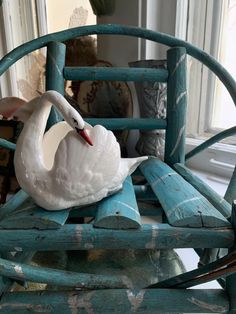 a white swan sitting on top of a wooden chair