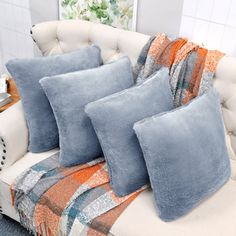 four blue pillows sitting on top of a white couch