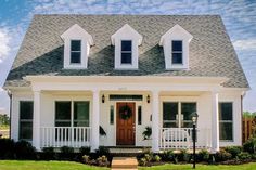 a white house with black shutters on the front and side doors, windows, and porch