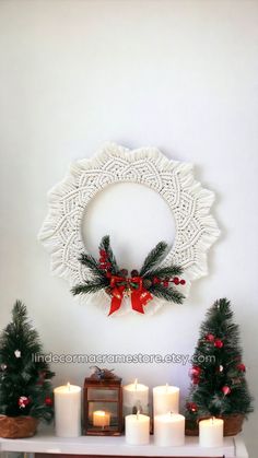 a table with candles and christmas decorations on it, next to a wall hanging wreath