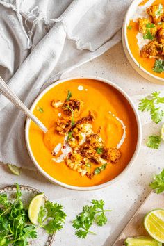 two bowls filled with carrot soup and garnished with cilantro