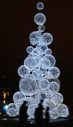 a white christmas tree with lots of balls on it's top in the dark