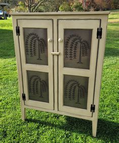 an old cabinet is painted white and has trees etched on the glass panels in it